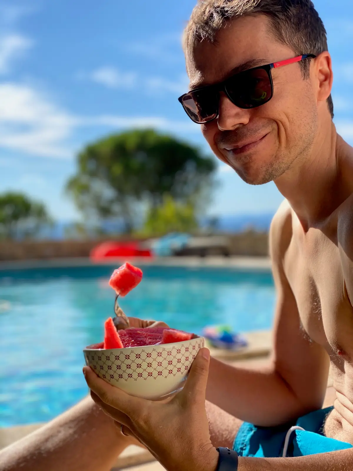 Arnaud Joubay by a pool, sunglasses on, eating watermelon
